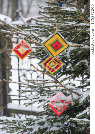 Multicolored wool Christmas tree decorations hanging on the a Christmas tree 135872260