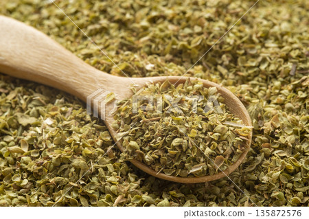 Organic dried oregano leaf on a wooden spoon on a pile dried leaves Organic dried oregano leaf on a wooden spoon on a pile dried leaves 135872576