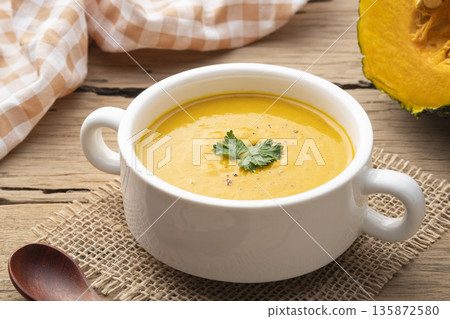 pumpkin carrot cream soup in white bowl,garnished with parsley.Healthy food 135872580