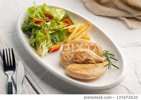 Grilled Black Pepper Chicken fillet with green oak lettuce ,tomatoes,carrot,french fries and onion in white plate. 135872620