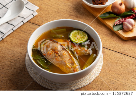 Chak sohm sour curry (gaaeng chak sohm),Thai Sour soup made of Tamarind Paste with striped catfish ,Kaffir Lime and water spinach in white bowl. 135872687