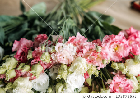 Bunches of pink and white lisianthus flowers lie flat on brown paper. Eryngium alpium, goldenrod, floristry workshop, slow living, hand-gathered bouquets. 135873655
