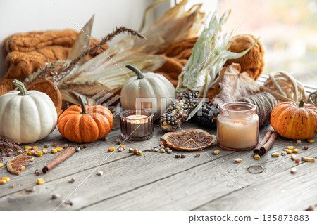 Autumn background with candles, pumpkins, corn and knitted element. Autumn background with candles, pumpkins, corn and knitted element. 135873883