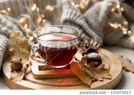 Autumn composition with a cup of tea, leaves and a knitted element. Autumn composition with a cup of tea, leaves and a knitted element. 135873913