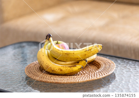 A bunch of bananas and apples in a plate in the interior of the room. 135874155
