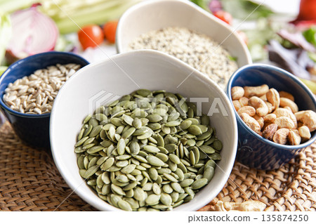 Close-up, a bowl of pumpkin seeds and other healthy foods on the kitchen table. Close-up, a bowl of pumpkin seeds and other healthy foods on the kitchen table. 135874250