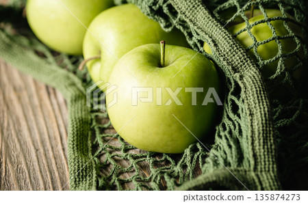 Close-up, green apples in a mesh shopping bag. Close-up, green apples in a mesh shopping bag. 135874273