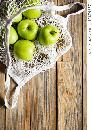 Close-up, green apples in a mesh shopping bag, top view. 135874277