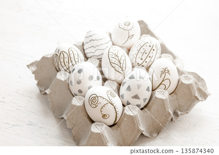 Close-up, a tray with hand-painted Easter eggs on a white background. 135874340
