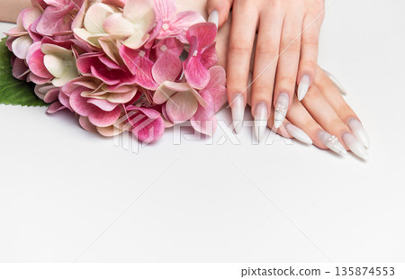 Woman showcasing elegant long almond nails with floral art 135874553