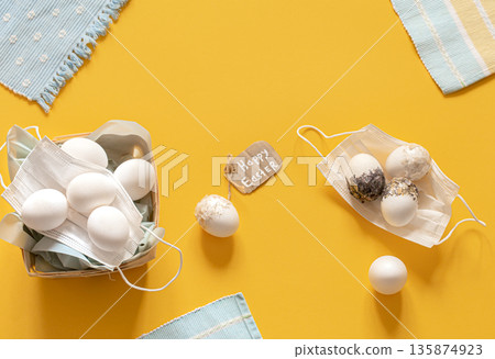 Easter composition with protective masks and scattered Easter eggs top view. Easter composition with protective masks and scattered Easter eggs top view. 135874923