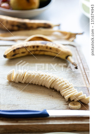 Sliced ripe banana fruit on wooden cutting board. 135874943