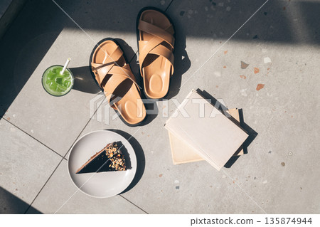 Slippers, lemonade and books on tiles by the pool, top view. Slippers, lemonade and books on tiles by the pool, top view. 135874944