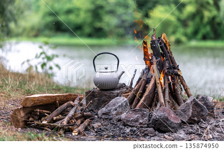 Small kettle is heated on a bonfire, outdoor recreation concept. 135874950