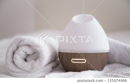 Spa composition with aroma diffuser and towel on a blurred background. 135874986
