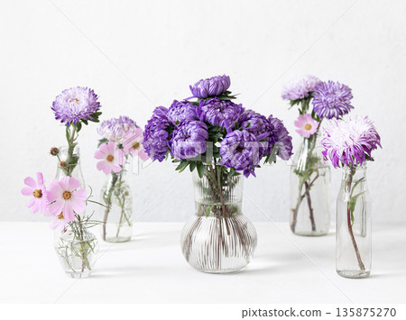 Glass vases with fresh chrysanthemum flowers on a blurred white background. Glass vases with fresh chrysanthemum flowers on a blurred white background. 135875270
