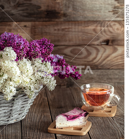 Spring composition lilac flowers in a basket on a wooden background. 135875278