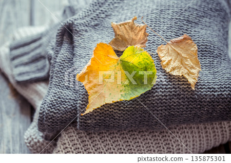 a stack of sweaters and autumn leaves a stack of sweaters and autumn leaves 135875301