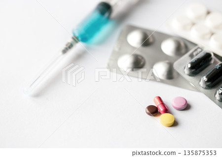 Syringe and pills on a white background isolated, close-up. Syringe and pills on a white background isolated, close-up. 135875353