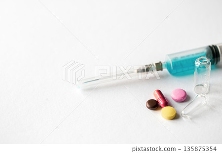Syringe and pills on a white background isolated, close-up. Syringe and pills on a white background isolated, close-up. 135875354