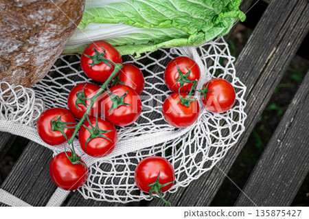 Vegetables and bread in a shopping bag on a wooden surface. 135875427