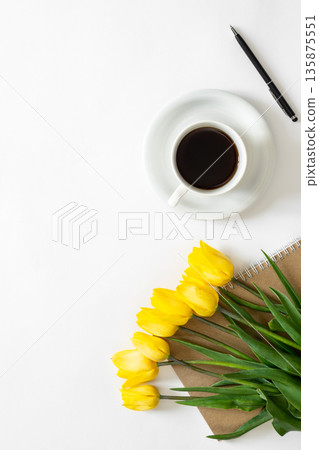A cup of coffee, bouquet of yellow tulips and a notebook on a white background. 135875551