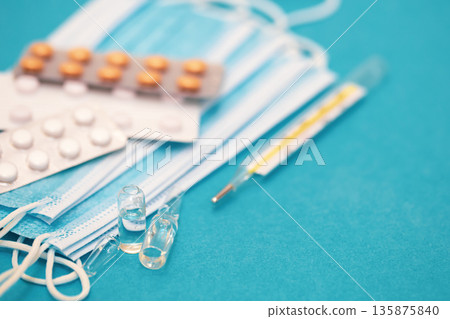 Medical background with thermometer, pills and masks close-up. 135875840
