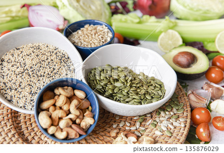 Pumpkin seeds, nuts and chia seeds and other healthy foods on the kitchen table. Pumpkin seeds, nuts and chia seeds and other healthy foods on the kitchen table. 135876029