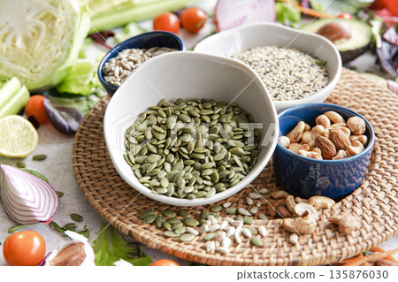 Pumpkin seeds, nuts and chia seeds and other healthy foods on the kitchen table. Pumpkin seeds, nuts and chia seeds and other healthy foods on the kitchen table. 135876030
