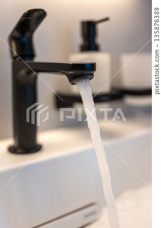 Black faucet stream. White basin. Modern hygiene Black faucet stream. White basin. Modern hygiene 135876389