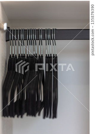 Black hangers in closet. Order and symmetry. Organized wardrobe. 135876390