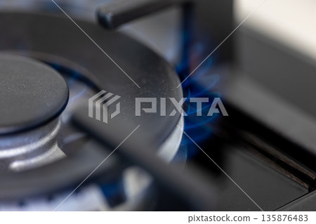 Close-up gas burner. Blue flame. Modern kitchen tech. Close-up gas burner. Blue flame. Modern kitchen tech. 135876483