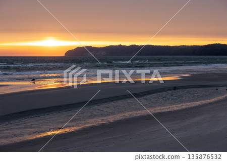 Golden sunset over sea and sandy beach. Peaceful evening by the shore. Golden sunset over sea and sandy beach. Peaceful evening by the shore. 135876532