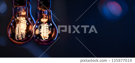 A burning lamps hangs in the dark on a blurred background. Space for text. 135877019