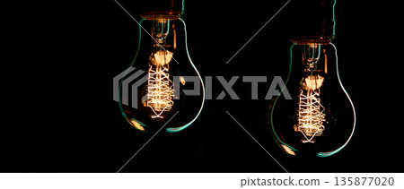 A burning lamps hangs in the dark on a blurred background. Space for text. A burning lamps hangs in the dark on a blurred background. Space for text. 135877020