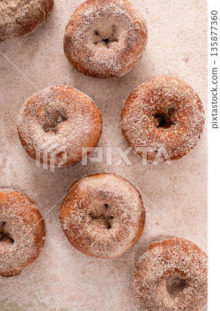 Apple cider or pumpkin spice donuts being covered in cinnamon sugar after baking Apple cider or pumpkin spice donuts being covered in cinnamon sugar after baking 135877360