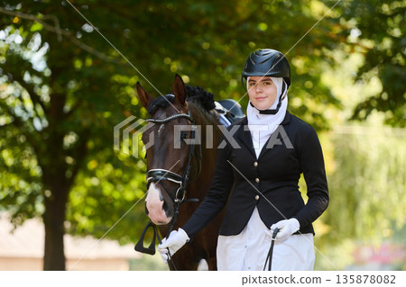 Equestrian woman in hijab with horse in nature, riding attire, competitive sport, outdoor lifestyle, professional rider, horse and rider, equestrian fashion, horse riding 135878082