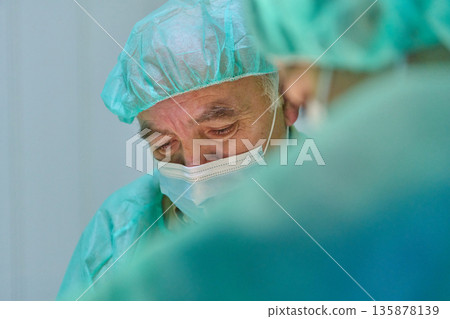 Focused Surgeon in Sterile Operating Room Wearing Mask and Cap During Surgery Focused Surgeon in Sterile Operating Room Wearing Mask and Cap During Surgery 135878139