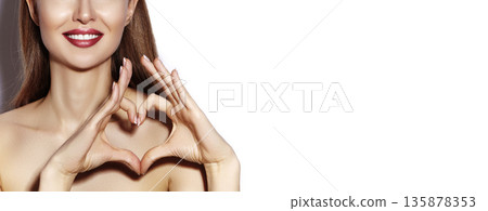 Smiling beautiful woman forming heart shape with hands. Valentine Day concept, happy girl, bright makeup for date, red lipstick. Beauty mockup for cosmetic branding, romantic mood, feminine style. Smiling beautiful woman forming heart shape with hands. Valentine Day concept, happy girl, bright makeup for date, red lipstick. Beauty mockup for cosmetic branding, romantic mood, feminine style. 135878353