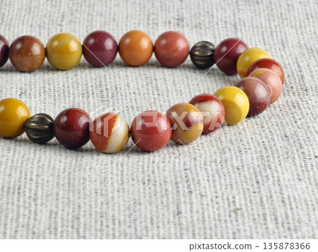 Prayer beads made of mukaite jasper against a burlap background. Close-up. Detail. Selective focus. Prayer beads made of mukaite jasper against a burlap background. Close-up. Detail. Selective focus. 135878366