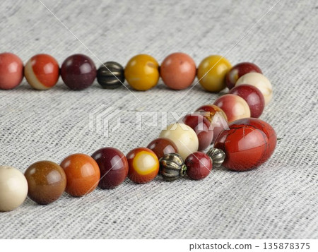 Prayer beads made of mukaite jasper against burlap background. The 33-bead prayer beads are traditionally used for meditation by people of various faiths. 135878375