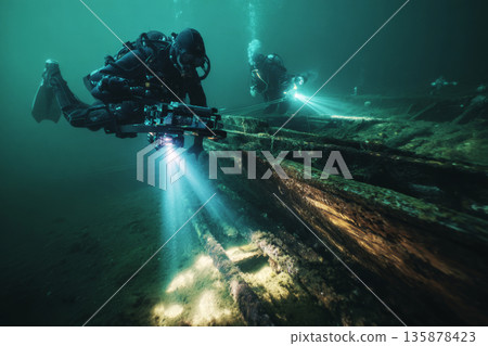 Diver explores a wrecked wooden hull as a small ROV uses its arms to inspect various details of the sunken structure underneath the water 135878423