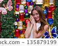 Happy woman posing at colorful Christmas decoration with festive gems and tinsel 135879199