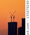 Silhouettes of skyscrapers and construction cranes against the sunset sky 135879249