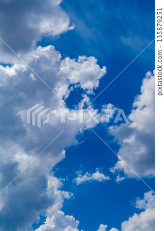 Vertical photo of white clouds against a blue sky, the edges of which are illuminated by lateral sunlight. Weather phenomena, synoptic forecasts. Natural environment theme Vertical photo of white clouds against a blue sky, the edges of which are illuminated by lateral sunlight. Weather phenomena, synoptic forecasts. Natural environment theme 135879251