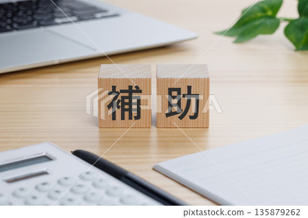 A block with the word "assistance" written on it on the table A block with the word "assistance" written on it on the table 135879262