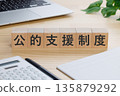 桌上放著一個寫著「公共援助系統」字樣的方塊。 135879292