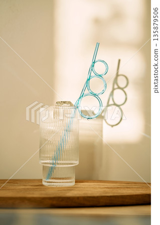 Refreshing drink with ice and blue straw creating shadow 135879506