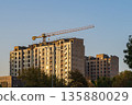 Multi-story building under construction with tower crane against blue sky. Industrial facilities, real estate in phase of walls construction , urban development, renovation, housing stock renewal 135880029