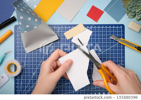 Making a gnome in love craft. Hands cut out a beard from white paper. Creative process. Making a gnome in love craft. Hands cut out a beard from white paper. Creative process. 135880396